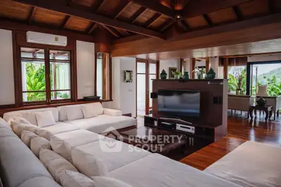 Luxurious living room with elegant wooden ceiling and large white sectional sofa, offering a serene garden view.
