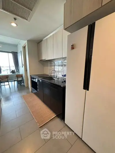 Modern kitchen with sleek cabinets and spacious dining area in open layout apartment.