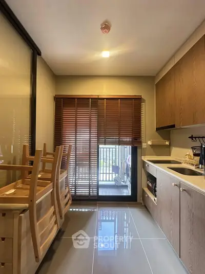 Modern kitchen with sleek cabinetry and dining area, featuring natural light and stylish wooden blinds.