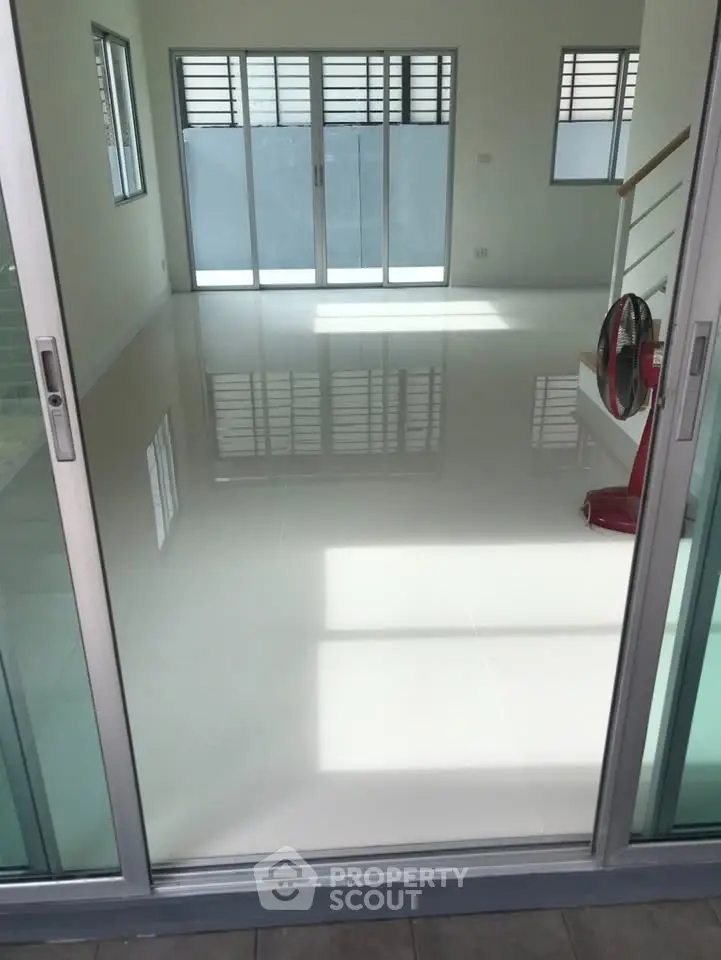 Spacious modern living room with large windows and sleek white flooring.