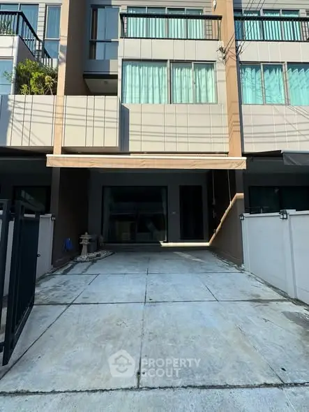 Modern townhouse exterior with driveway and balcony, perfect for urban living.