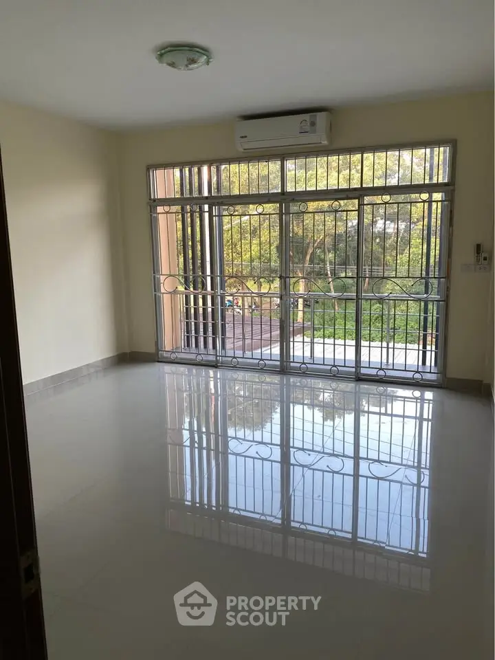 Spacious living room with large windows and serene garden view, perfect for relaxation and natural light.
