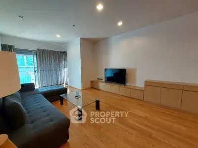 Spacious modern living room with sleek wooden flooring and large sofa, perfect for relaxation.