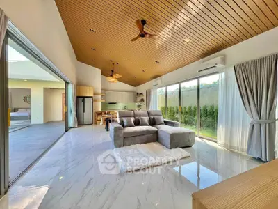 Spacious modern living room with open layout and garden view, featuring elegant ceiling design and plush furniture.