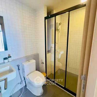 Modern bathroom with glass shower and sleek fixtures in contemporary apartment.