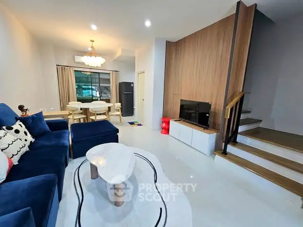 Modern living room with stylish furniture and open layout, featuring a cozy blue sofa and elegant decor.