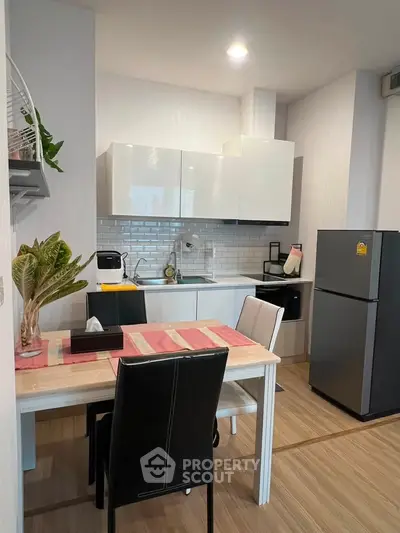 Modern kitchen with sleek white cabinets and dining area in stylish apartment.