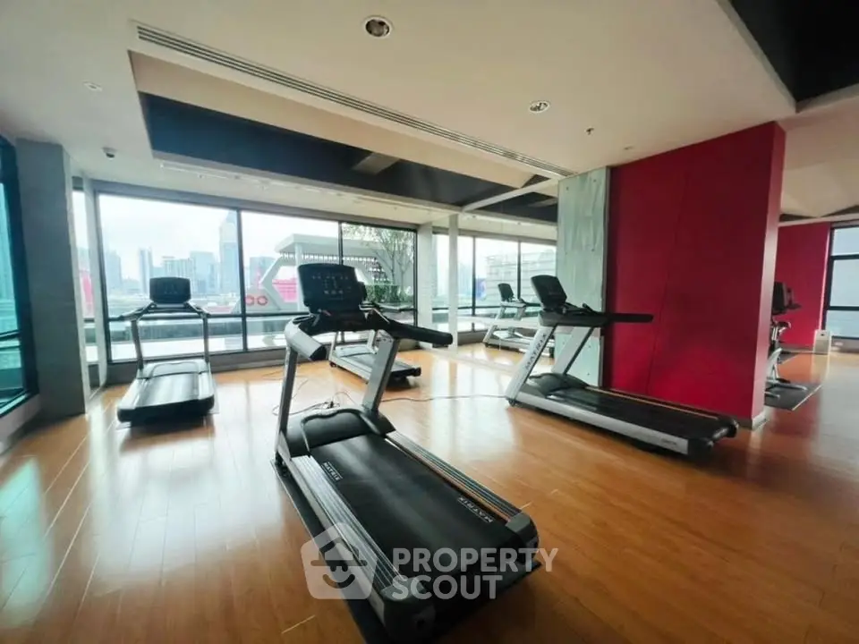 Modern gym with city view and state-of-the-art equipment in luxury building.