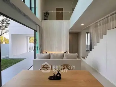 Modern open-plan living room with high ceilings and large windows overlooking a garden.
