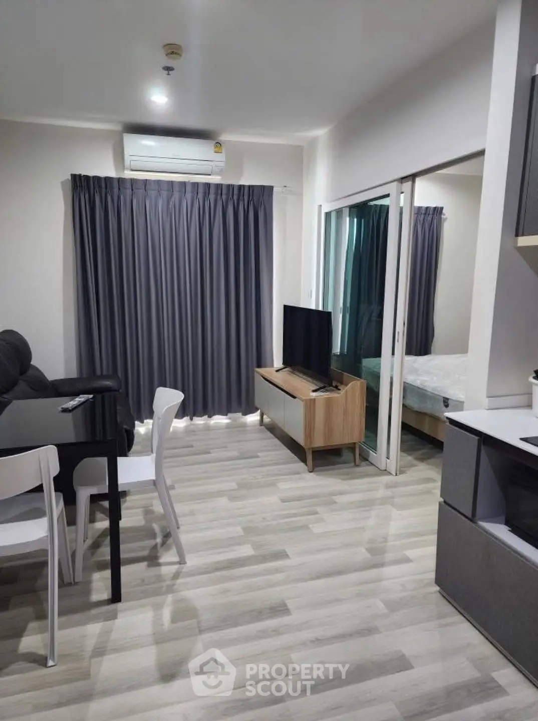 Modern living room with sleek furniture and open layout, featuring a cozy bedroom view.