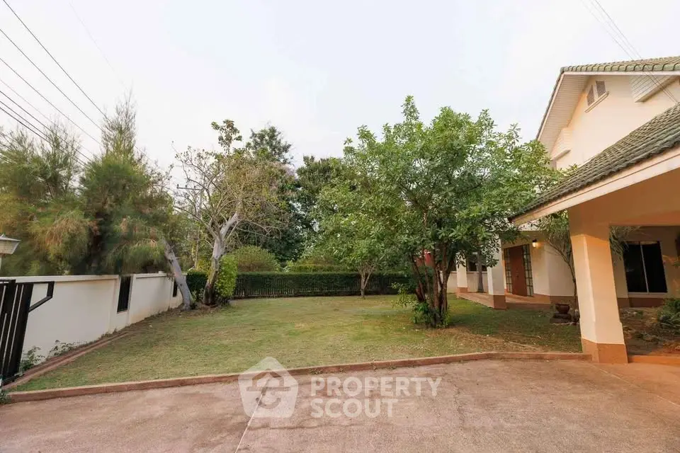 Spacious garden and driveway of a suburban home with lush greenery.