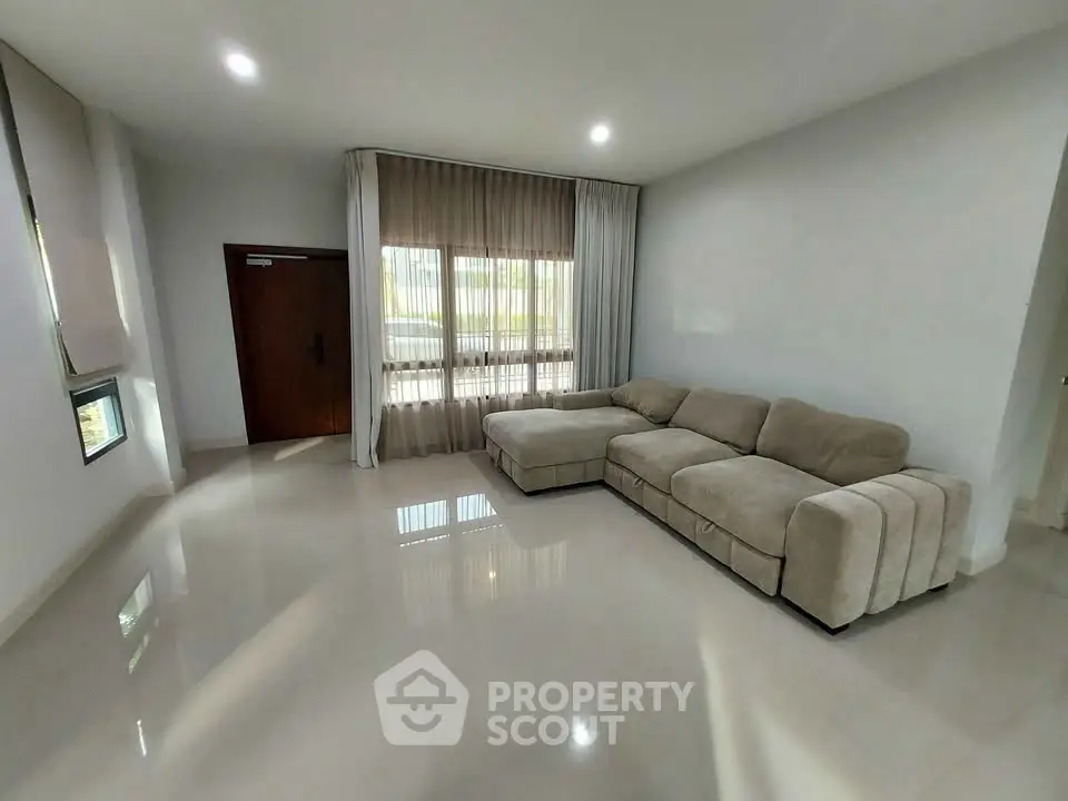 Spacious living room with modern beige sectional sofa and large window for natural light.