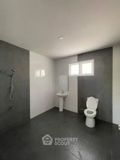 Spacious modern bathroom with sleek gray tiles and minimalist fixtures.