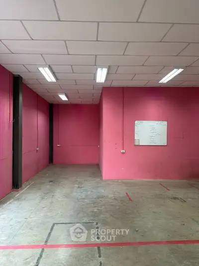 Spacious industrial space with vibrant pink walls and high ceiling lighting, perfect for creative ventures.
