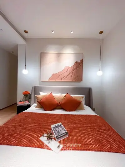 Elegant bedroom with modern decor and warm lighting, featuring stylish artwork and cozy bedding.