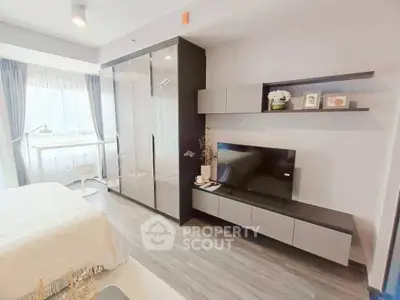 Modern bedroom with sleek storage and TV unit, bright natural light.