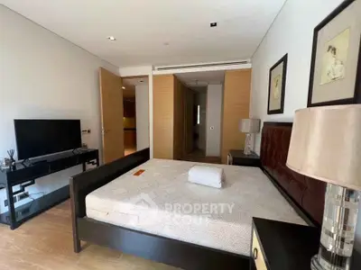 Spacious bedroom with modern furnishings and natural light, featuring a sleek TV stand and elegant decor.
