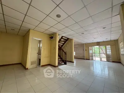 Spacious empty room with staircase and large windows, ideal for customization.