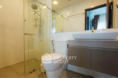 Modern bathroom with glass shower and sleek vanity in contemporary apartment.