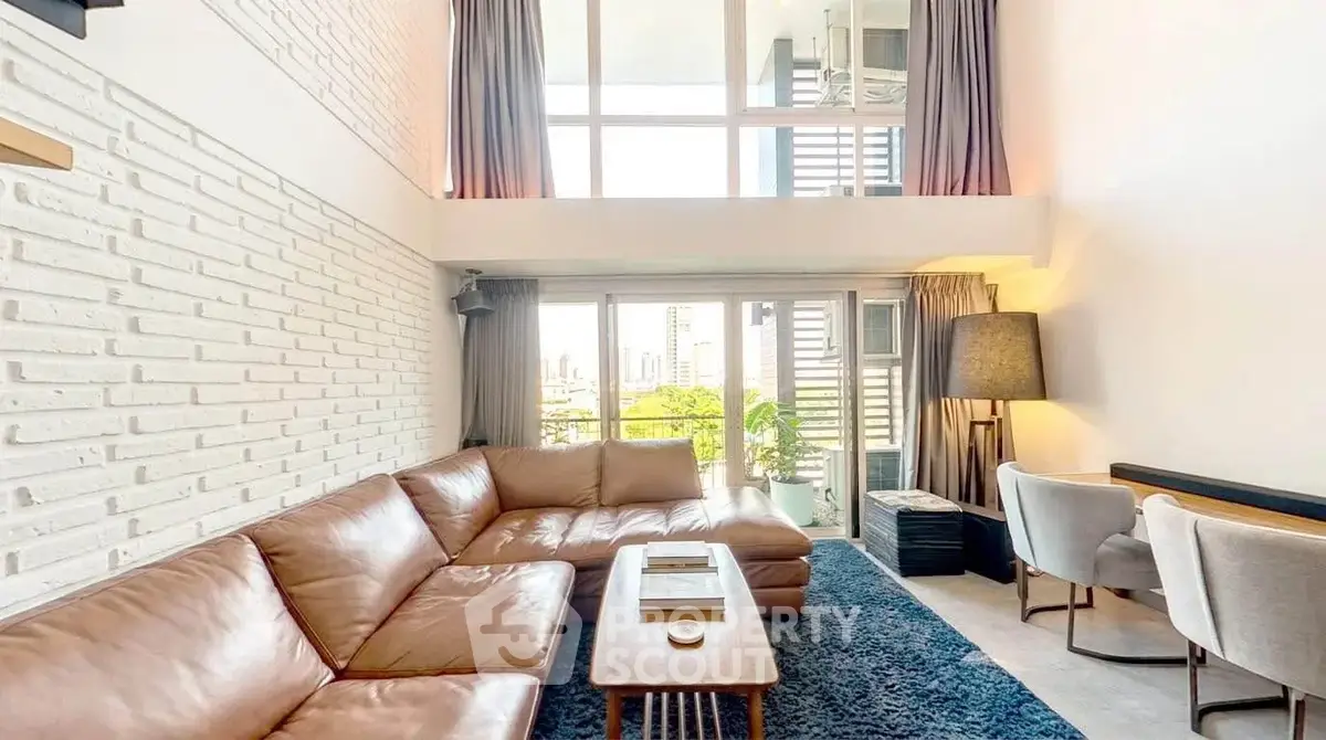 Spacious modern living room with high ceilings and large windows offering city views.