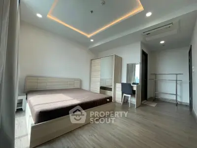 Spacious modern bedroom with wooden flooring and stylish furniture