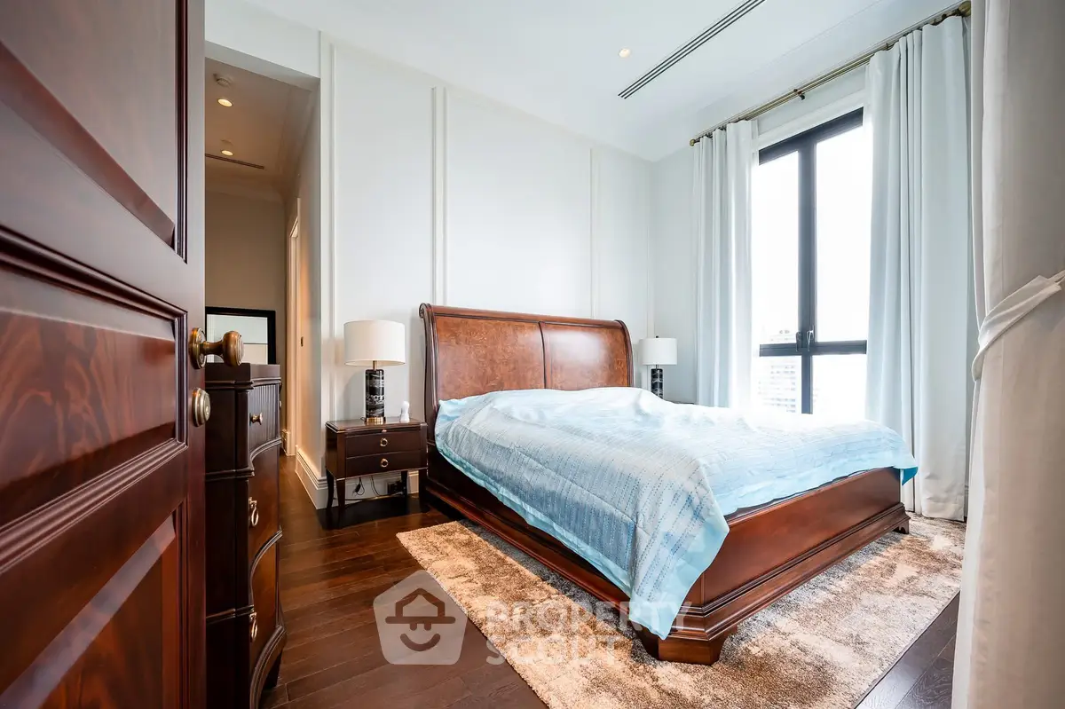 Luxurious bedroom with elegant wooden furniture and large window view.