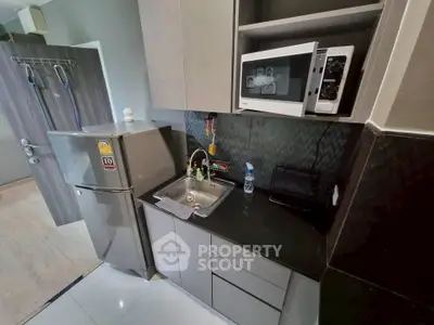 Modern compact kitchen with fridge, microwave, and sleek cabinetry