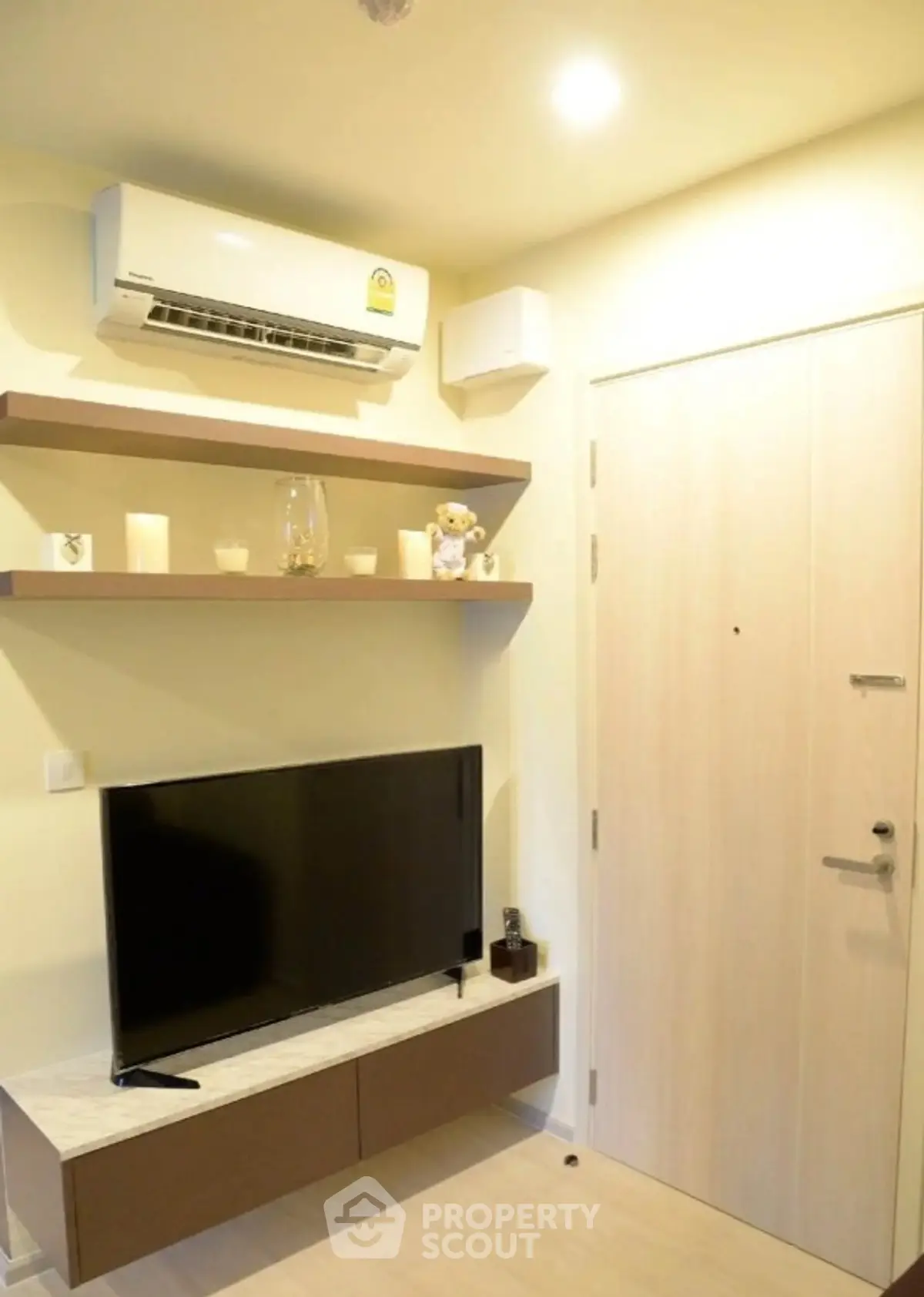 Modern living room with TV, air conditioning, and stylish shelving.