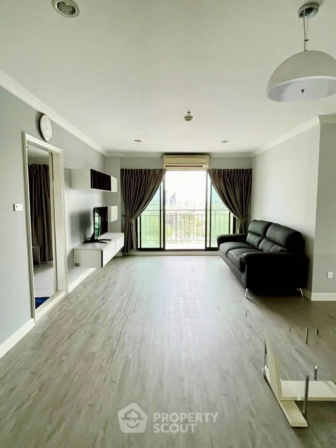 Spacious modern living room with balcony and scenic view, featuring sleek flooring and elegant decor.