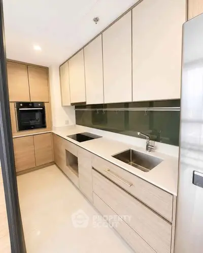 Modern kitchen with sleek cabinetry and built-in oven in a contemporary apartment.