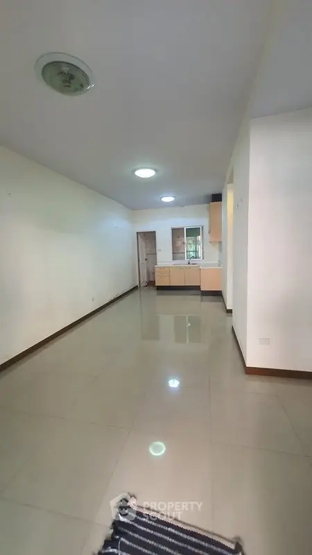 Spacious open-plan living area with tiled flooring and modern kitchen.