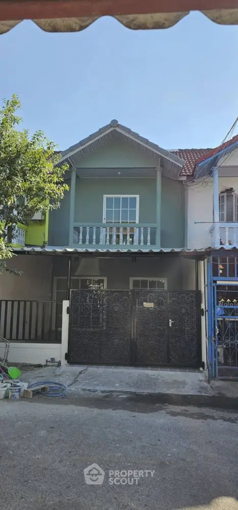 Charming two-story house with balcony and gated entrance in a serene neighborhood.
