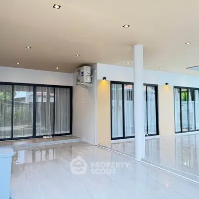 Spacious modern living area with large windows and sleek flooring, perfect for natural light and open living.