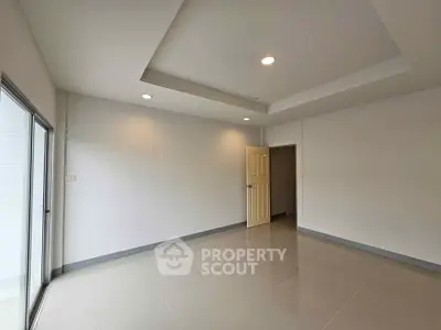 Spacious empty room with modern recessed lighting and large window.