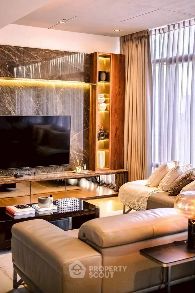 Luxurious living room with modern decor, large TV, and elegant lighting.