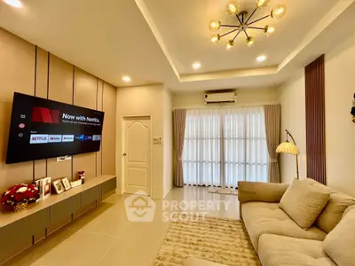 Modern living room with stylish lighting and cozy sofa, featuring a wall-mounted TV and elegant decor.