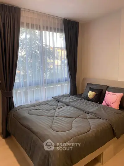 Cozy bedroom with large window and elegant curtains, perfect for relaxation.