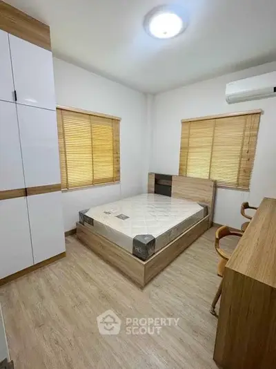 Modern bedroom with wooden furniture and natural light, featuring a comfortable bed and ample storage space.