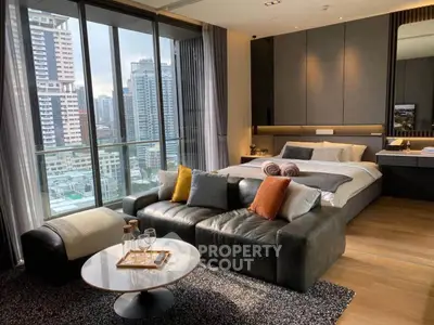 Luxurious bedroom with city view, modern furnishings, and cozy seating area.