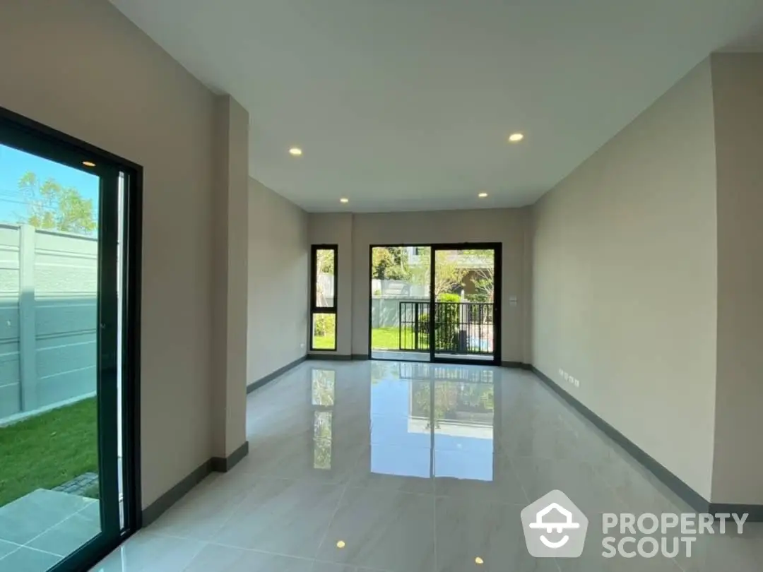 Spacious and bright living room with glossy tiled floors, large windows, and direct garden access, perfect for modern living.