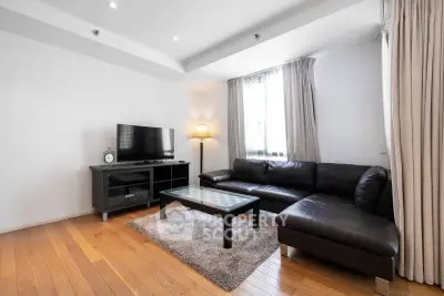 Spacious modern living room with sleek leather sofa and large TV, perfect for relaxation.