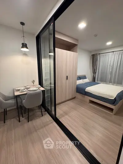 Modern studio apartment with sliding glass partition and cozy dining area