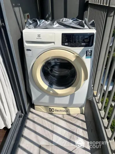 Modern Electrolux washing machine on a sunny balcony with sleek railing.