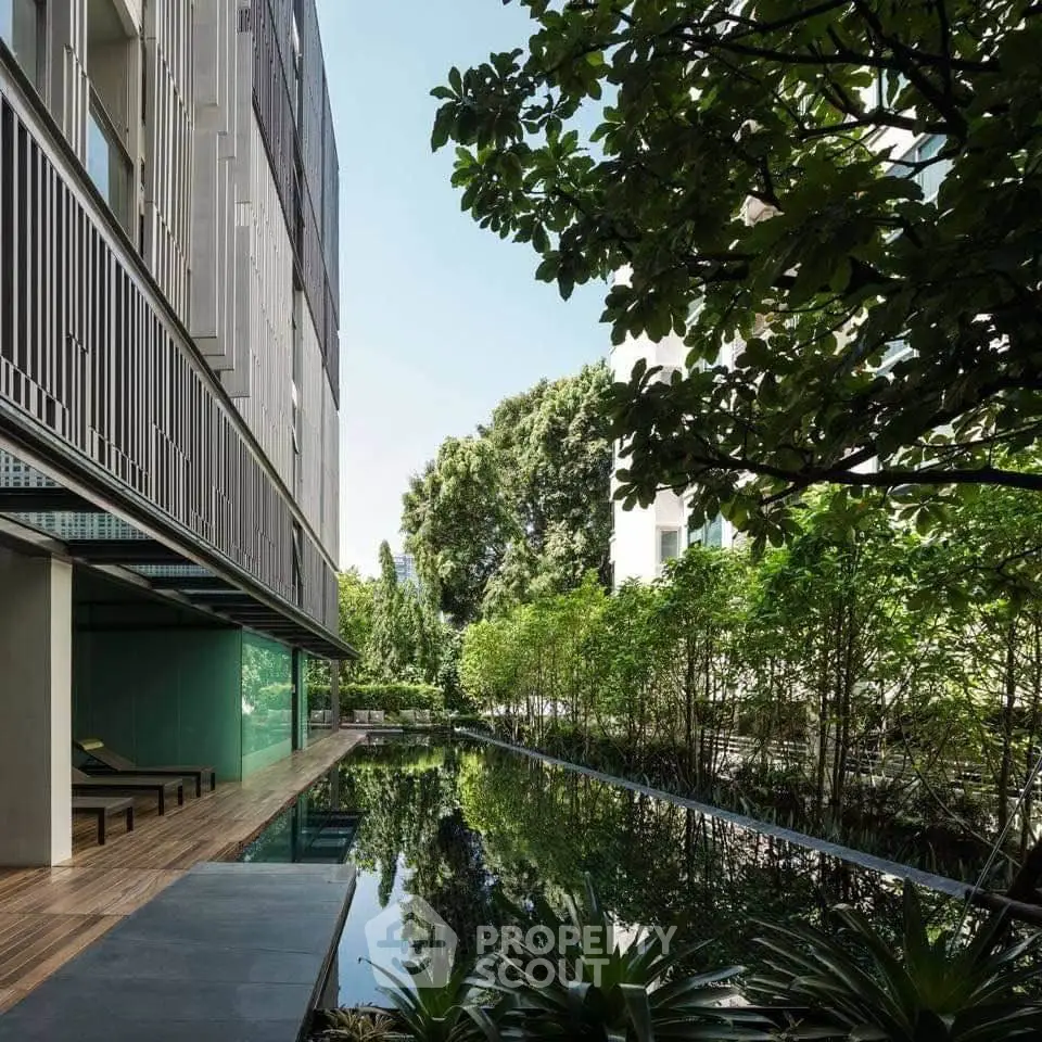 Luxurious modern building exterior with serene garden and reflective water feature.