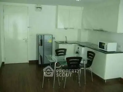 Modern kitchen with dining area, sleek appliances, and minimalist design in a compact space.