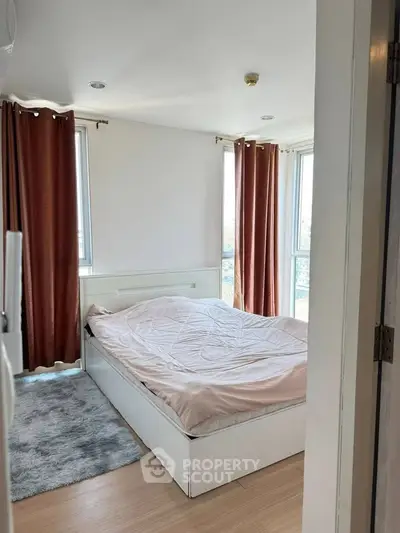 Cozy bedroom with large windows and modern decor in a high-rise apartment.