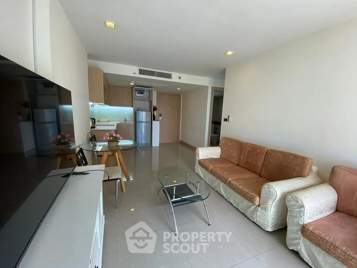 Modern living room with open kitchen, stylish furniture, and natural light.