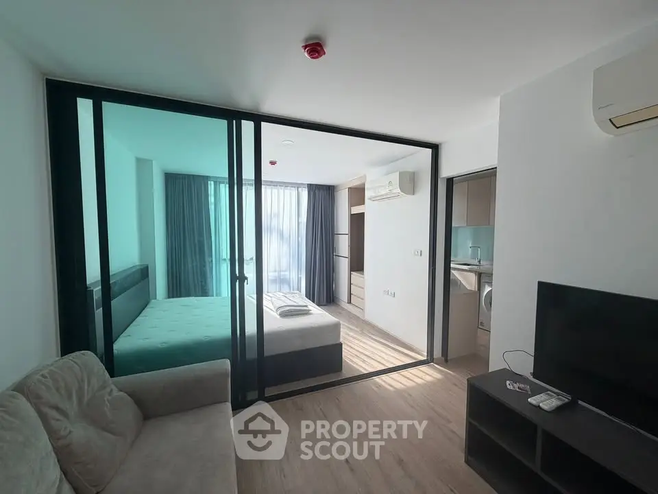 Modern studio apartment with glass partition, cozy living area, and natural light.