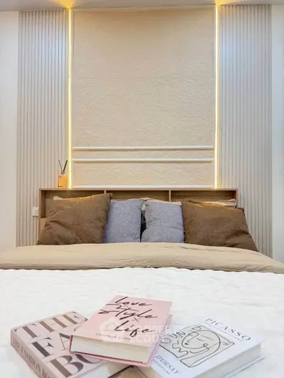 Cozy bedroom with modern design, featuring stylish lighting and decorative books on a plush bed.