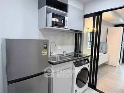 Modern kitchen with sleek appliances including fridge, microwave, and washing machine in compact layout.